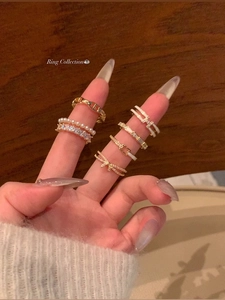 Close-up of a stacked ring set featuring bow knot, pearls, and H-shaped gold designs