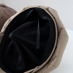 Detail view of the brown plaid beret cap lining with adjustable inner drawstring