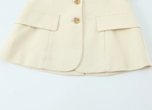 Détail du haut blazer sans manches beige avec poches à rabat et boutons aspect ambre