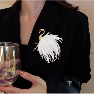 Detail of white feather flamingo brooch with gold plating and zircons on a black blazer