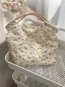 Close-up of floral canvas tote bag with woven handles inside a white mesh cart
