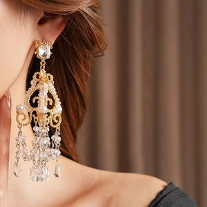 Detail of gold chandelier earrings with crystals and pearls worn by a model