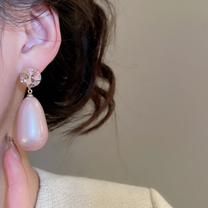 Close-up of elegant pink teardrop pearl earrings with faceted crystals on a model