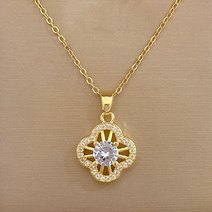 Macro shot of gold clover pendant with pavé set crystals and central round gemstone