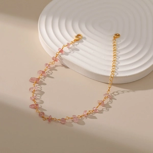 Detailed shot of 18K gold chain bracelet with pink crystal stones on white wave display