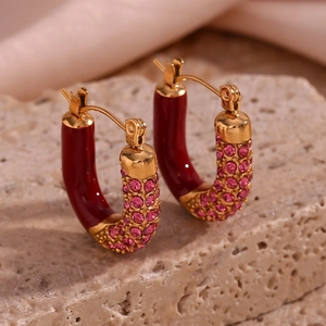Macro view of gold-plated U-shaped earrings with red enamel and pink zircon stones