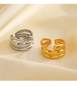 Detail of chunky gold and silver layered open rings on beige silk fabric backdrop