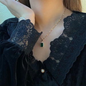 Vintage emerald crystal necklace with gold chain worn by a model in black lace