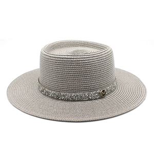 Detailed texture of gray straw boater hat with sequined band and gold M logo