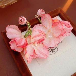 Detail von Blumenohrringen mit rosa Stoffblüten und eleganten grünen Perlenquasten