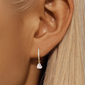 Macro shot of gold heart-shaped zircon earrings with cubic zirconia pavé on ear wire