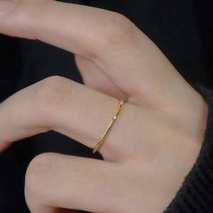 Minimalist thin 18K gold plated ring with single round zircon on a model's hand