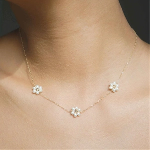 Detailed view of delicate 14K gold plated necklace with three small pearl flower charms
