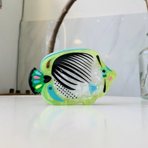 Detailed view of the neon green fish-shaped hair claw clip with colorful mosaic texture