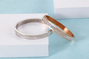 Détail de joncs argent et or rose avec strass pavés sur des blocs géométriques blancs