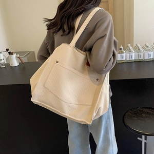 Detail view of cream waffle texture canvas tote bag with front pocket and metal rivets