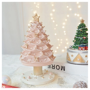 Detail view of pink Christmas tree music box with gold stars and white snowflakes