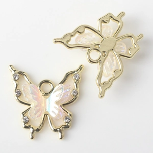 Macro detail of alloy butterfly pendant with pearl resin wings and small white rhinestones