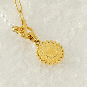 Detail of gold pearl necklace with OT toggle clasp and embossed heart gear pendant