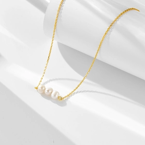 Close-up of three natural pearls on a delicate gold 925 silver chain necklace