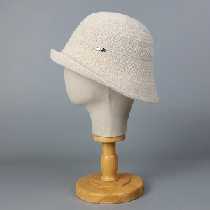 Chic cream knit bucket hat with rolled edge and metallic detail on a studio stand