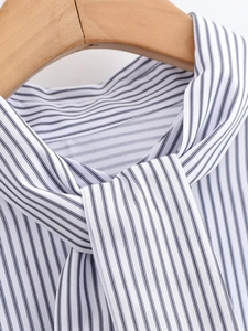 Close-up of the elegant bow-tie neckline and blue striped poplin fabric detail