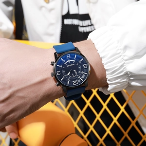 Close-up of men's watch with blue silicone strap and black dial worn on a wrist