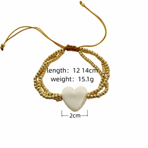Detalle de pulsera artesanal de cuentas doradas con corazón blanco y medidas