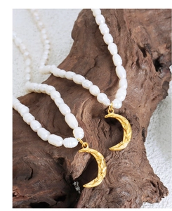 Detail of freshwater pearl necklace with golden crescent pendant on natural wood