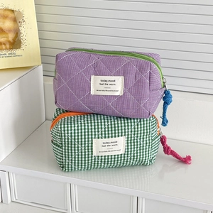 Detail of plaid quilted cosmetic bags with woven rope zippers and fabric label