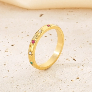 Gros plan sur bague en acier inoxydable doré avec gemmes colorées et détails étoilés