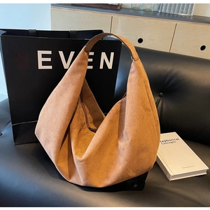 Detail of tan suede hobo bag with soft draping folds and dark metallic zipper closure