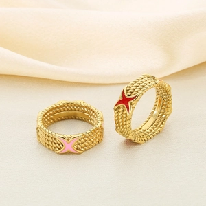 Detail of gold rings with pink and red X-shaped enamel and textured rope patterns