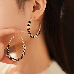 Gros plan de boucles d'oreilles créoles léopard et métal doré portées par un mannequin