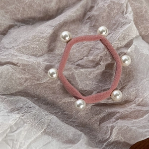 Detail of pink elastic hair tie decorated with six elegant white pearls on textured background