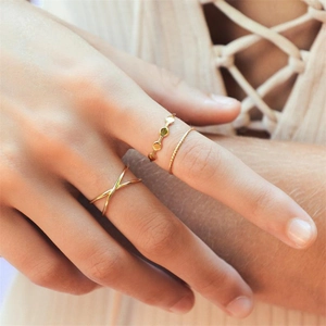 Close-up of three layered gold-tone rings including a green gemstone and twisted band