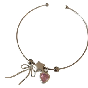 Silver open bangle with pink heart zircon, star and bow charms in a minimalist style