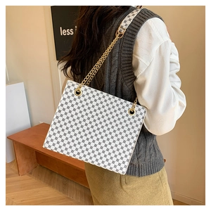 Detailed back view of a white tote bag with black geometric patterns and gold chain straps