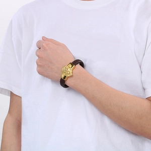 Close-up of woven brown leather bracelet with golden lion head clasp on model's wrist