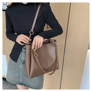 Chic brown leather tote bag with elegant gold ring and chain shoulder strap detail