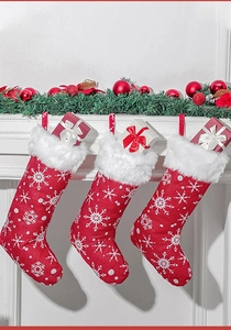 Three red Christmas stockings with snowflake embroidery and plush trim on a fireplace
