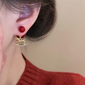 Gros plan sur un clou en perle rouge et une boucle d'oreille cheval à bascule