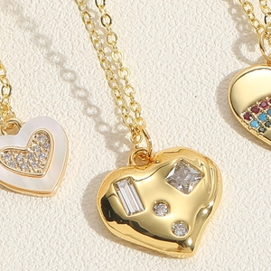 Detailed macro view of heart pendants with shell inlay and zircon accents in gold finish