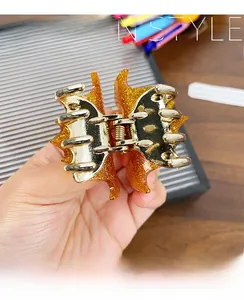Macro detail of sparkly orange acrylic bat hair claw with gold metal mechanism