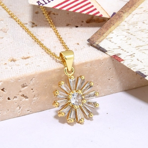 Macro detail of a gold sun flower necklace with shiny cubic zirconia petals on stone