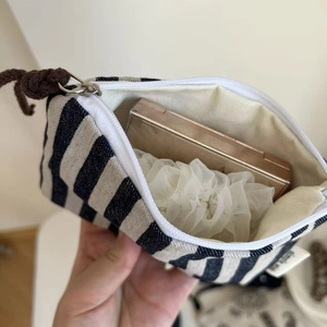 Internal view of a small striped canvas pouch storing cosmetics with a zip closure