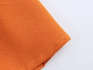 Détail de la robe de plage orange en coton et lin avec texture et coutures soignées