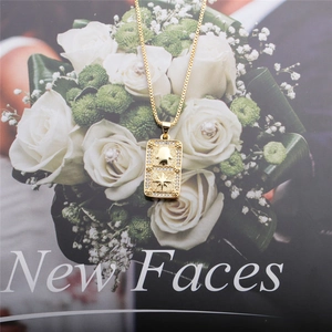 Detailed shot of golden Hamsa Hand pendant with zircon stones on a floral background