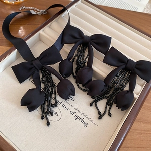 Detail of elegant black fabric bow earrings with crystal fringe in jewelry tray