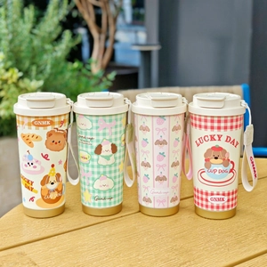 Row of colorful stainless steel coffee mugs with cute dog illustrations on a wooden table